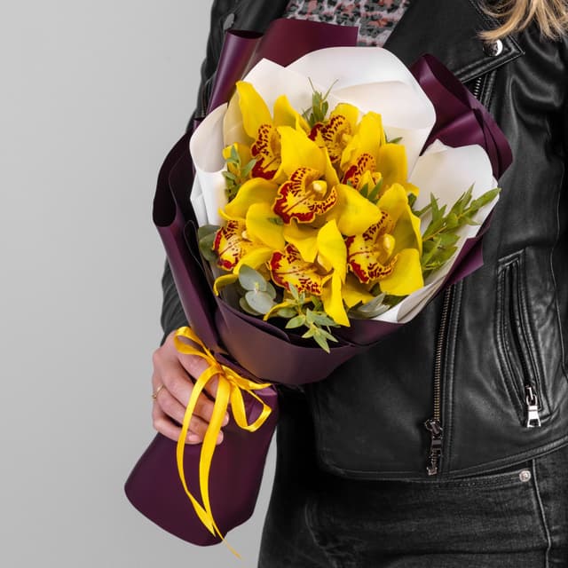 Шикарный букет из 7 желтых Орхидей в матовой бумаге с зеленью Шикарный букет из 7 желтых Орхидей в матовой бумаге с зеленью